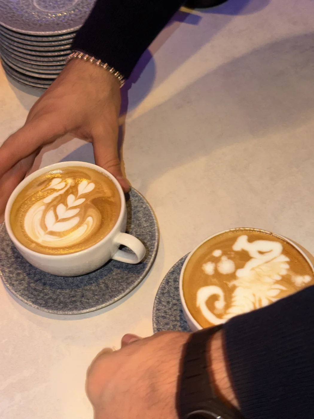 Barista serviert zwei Tassen mit Latte Art